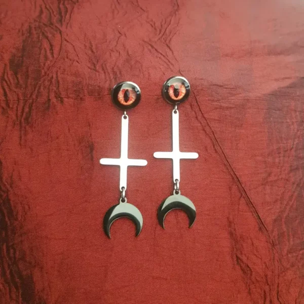 Ces boucles d'oreilles Lilith mère des démons arbore oeil démoniaque et croix satanique, avec finition croissant de lune noire. En acier inoxydable.