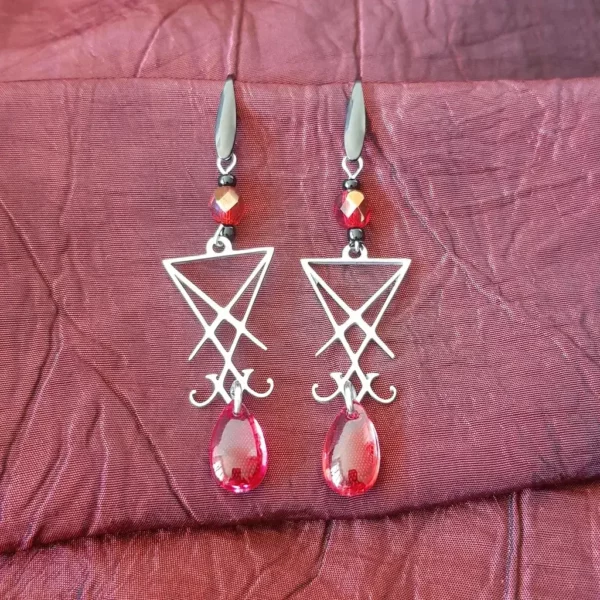 Ces boucles d'oreilles sigil de Lucifer seront parfaite pour un look gothique, à la fois démoniaque et angélique. La finition perle rouge évoque une goutte de sang, relevé par le contraste noir argent du restant du bijou.