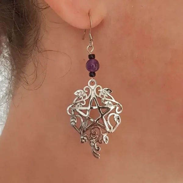 Acier inoxydable et améthyste, pierre et métal, voila un ensemble avec une touche de couleur pour ces boucles d'oreilles pentagramme witchy. Et une pointe de verre noir pour faire ressortir le tout!